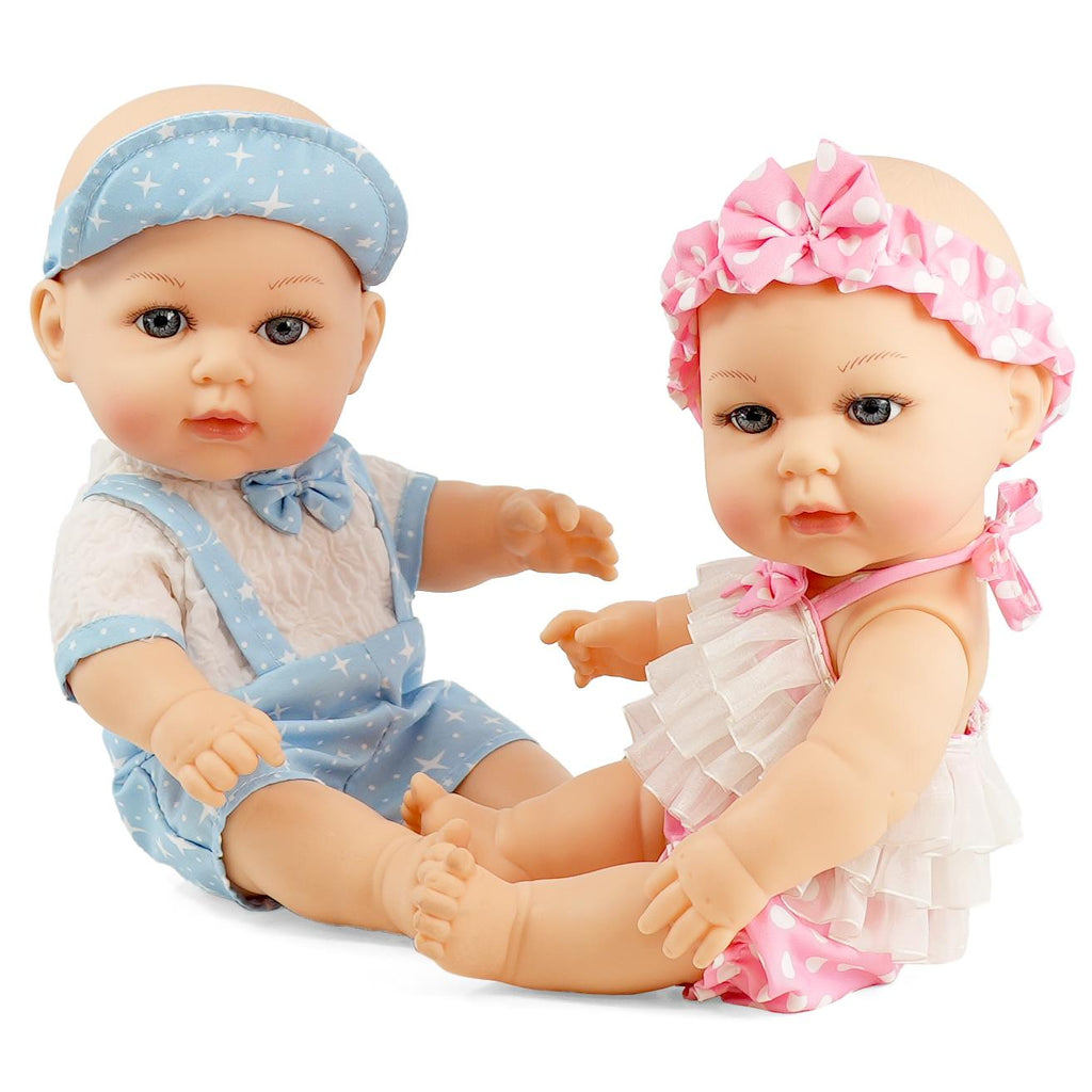 Two anatomically correct 14-inch twin dolls sit on the floor, one dressed in a blue romper with a white star pattern and headband, and the other in a pink and white ruffled swimsuit with a matching headband. They have detailed facial features and soft bodies, ideal for play and display. Perfect for nurturing play, collectible doll enthusiasts will love these twins, BiBi Dolls Lucy & Lou.